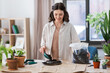 © Syda Productions - people, gardening and housework concept - happy woman with trowel and soil in bag planting flowers in glass vase at home