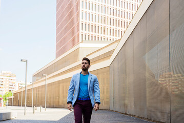 Young bearded man in casual clothes walking on the street