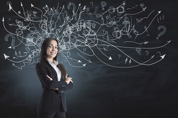 Portrait of attractive thoughtful young european businesswoman standing on chalkboard/blackboard wall background with arrows mesh sketch. Confusion and question concept.