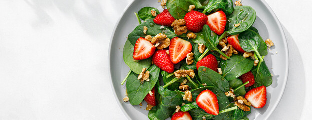 Strawberry and spinach salad with walnuts. Top view. Banner