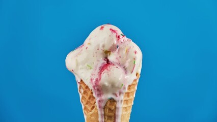 timelapse of vanilla ice cream with strawberry topping and colorful sprinkles in waffle cone melting