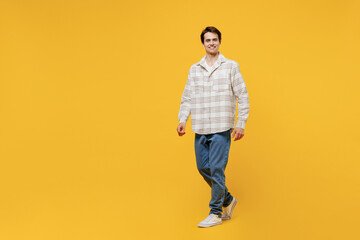 Full body young smiling happy cheerful caucasian man 20s wearing white casual shirt walking going strolling look camera isolated on plain yellow background studio portrait. People lifestyle concept.