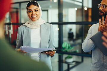 Wall Mural - Cheerful Muslim manager holding a business meeting with her team