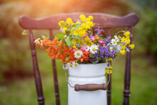 Bukiet Wiosennych, Polnych Kwiatów W Rustykalnym Klimaci W Kance Na Mleko Na Starym Krześle W Ogrodzie W Promieniach Słońca, Wiejskie Klimaty