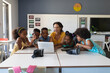 © WavebreakMediaMicro - Young female caucasian teacher teaching laptop to african american elementary students in class
