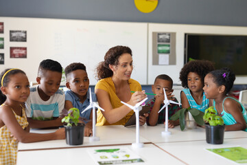 Wall Mural - African american elementary students listening to caucasian young female teacher showing windmill