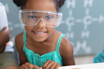 Wall Mural - Portrait of smiling african american elementary schoolgirl wearing protective eyewear in laboratory