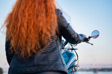 Rear View Of Red-haired Curly Woman In Leather Clothing Motorcycle Outdoors.