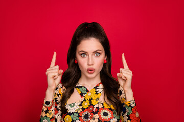 Portrait of attractive amazed girl funky hairdo demonstrating up copy blank space isolated over bright red color background