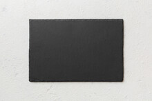 Top View Of Empty Black Slate Plate On Cement Background. Empty Space For Your Design