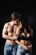© LIGHTFIELD STUDIOS - Muscular man hugging brunette woman in bra isolated on black.