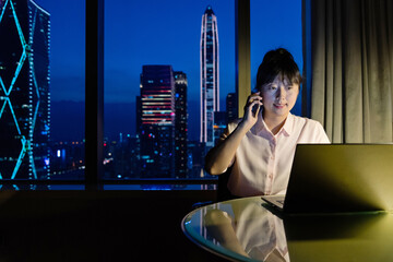 Wall Mural - Woman working with laptop and cellphone at night