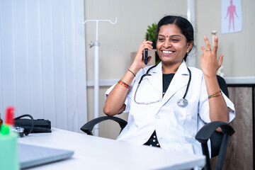 Happy doctor talking on mobile phone with Patients at hospital - concept of communication, taking break aand technology