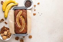 Traditional American Homemade Banana Bread With Chopped Walnuts, Chocolate And Cinnamon In Loaf Pan On Light Background. Fruit Cake. Healthy Vegan Desserts Concept. Top View, Copy Space.