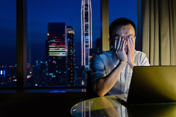 Tired man working with laptop at night