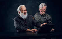 Shot Of Two Modern Senior Men With Gray Hairs Using Laptop Discussing Some Plans.