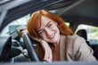 Young Woman Embracing Her New Car. Excited young woman and her new car indoors. Young and cheerful woman enjoying new car hugging steering wheel sitting inside