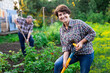 © caftor - woman farmer posing and digging in her estate garden