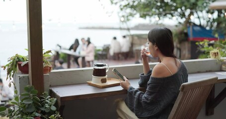 Canvas Print - Woman look at mobile phone and drink of hot tea at outdoor coffee shop