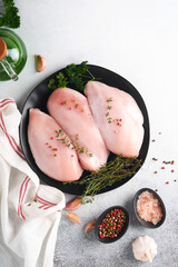 Wall Mural - Chicken breast. Raw chicken breast fillets on black ceramic plate on wooden cutting board with herbs and spices on old grey table background. Top view with copy space.