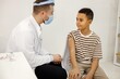 © prostooleh - Male doctor stick a band-aid to a boy after a vaccination