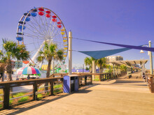 A Seaside Beach Boardwalk With A Ferris Wheel Under A Purple Sky.