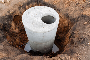 Canvas Print - Pit for sewerage installation of concrete rings in the pit, construction work on the site, gray color cement, open manhole, septic tank for the house.