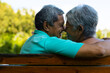 © wavebreak3 - Close-up of smiling biracial senior couple looking at each other while sitting on bench in park
