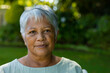 © wavebreak3 - Close-up portrait of confident biracial senior woman with short gray hair against plants in park