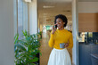 © WavebreakMediaMicro - Cheerful young african american businesswoman talking on smartphone holding coffee mug at workplace