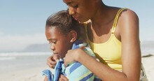 African american mother drying her daughter with a towel at the beach