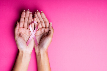 Wall Mural - Cropped hands of african american mid adult woman holding breast cancer awareness ribbon, copy space