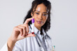 African american mid adult female doctor holding blood sample in test tube against white background