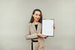 © bodnarphoto - Positive business woman holding a tablet with a blank white sheet in her hand and looking at the camera with a smile on her face.