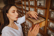 Beautiful lady in a white blouse looking for books in the archives of the old library, opened a drawer with information