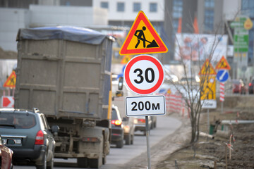 Wall Mural - Roadworks warning traffic signs of construction work on city street and slowly moving cars