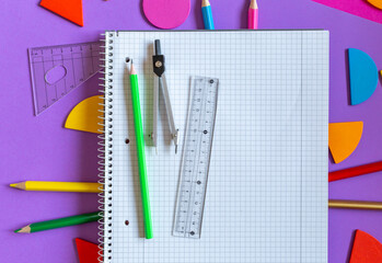 Wall Mural - School stationery on violet background. Colorful math fractions, rulers, open notepad on a purple background. Interesting, fun math for kids. Education, back to school concept