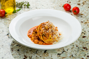 Wall Mural - Pasta fettuccine Bolognese with meat and parmesan on white plate on marble table