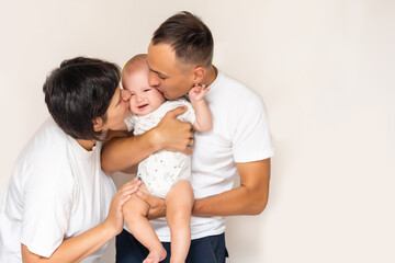 Wall Mural - Smiling young mother and father standing at home cradling the cute baby girl in their arms