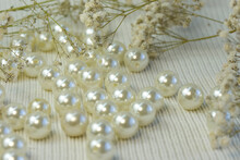 Bright Beautiful Whitw Pearl Beads Scattered On White Knitted Textured Background, Close Up