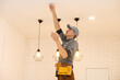 © Angelov - Young electrician installing smoke detector on ceiling