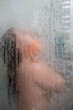 woman in shower view through glass covered with drops