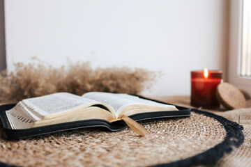 Wall Mural - Open Holy Bible on a old wooden table and white wall background. Religion concept. Cozy warm photo