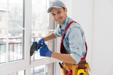 Wall Mural - Construction worker installing window in house. Handyman fixing the window with screwdriver