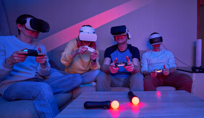 Wall Mural - friends playing virtual reality games using joysticks while sitting on the couch.