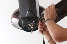 Close Up A Male Electrician Fixing And Installing A Ceiling Fan In A House.