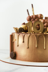 Wall Mural - Luxury birthday chocolate cake with drips decorated with candies covered with brown and golden cream cheese frosting