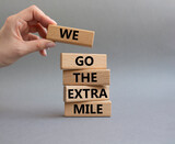 Fototapeta  - We go the extra mile symbol. Wooden blocks with words 'We go the extra mile'. Beautiful grey background. Businessman hand. Business and 'We go the extra mile' concept. Copy space.