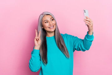 Photo of positive person make selfie hand fingers demonstrate v-sign isolated on pink color background