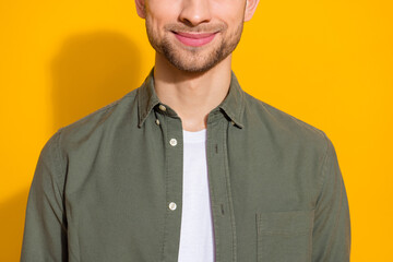 Wall Mural - Cropped view portrait of attractive cheerful well-groomed guy wearing khaki shirt isolated over vivid yellow color background